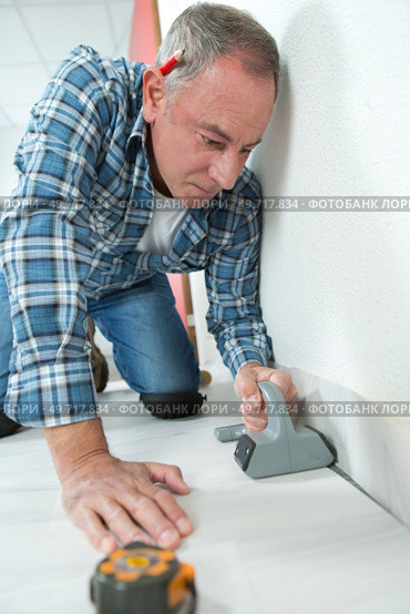 tiler marks the tile during the floor installation. Стоковое фото, агентство Ingram Publishing / Фотобанк Лори