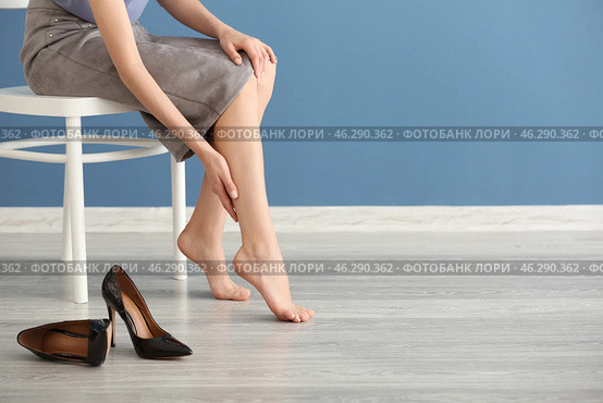 Tired young woman feeling ache in legs indoors. Стоковое фото, фотограф Pixel_shot / Фотобанк Лори