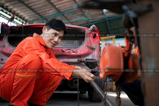 To return the automobile body to its former shape, an auto repair mechanic uses a machine to pull the car body caused by a heavy collision until it is deformed. Стоковое фото, агентство Ingram Publishing / Фотобанк Лори