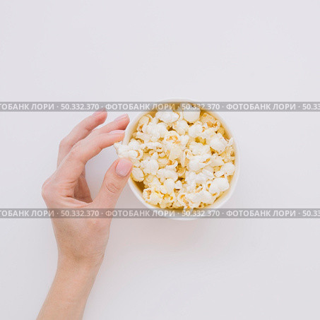 top view hand picking salted popcorn. High resolution photo. top view hand picking salted popcorn. High quality photo. Стоковое фото, агентство Ingram Publishing / Фотобанк Лори
