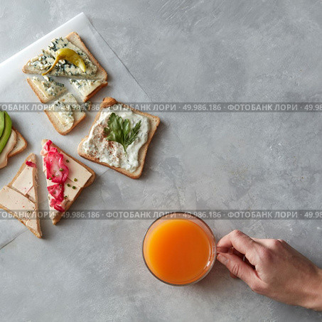 Top view of different kinds of sandwiches for tasting or having break isolated on table. Glass of orange juice not far from it. Sandwiches with cheese, avocado, etc.. Different kinds of sandwiches. Стоковое фото, агентство Ingram Publishing / Фотобанк Лори