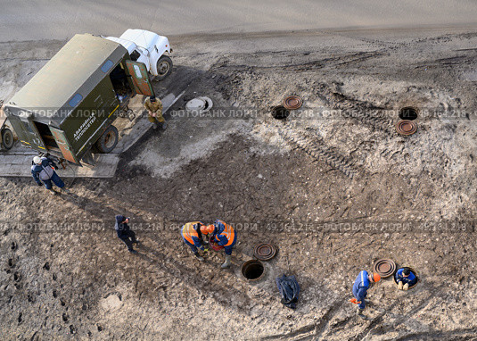 Top view of workers repairing underground heating mains through open hatches, the inscription on the truck: 'Emergency heating service' Стоковое фото, фотограф Сергей Фролов / Фотобанк Лори