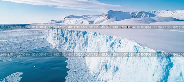 Tourists walking on snowy glacier near ocean in antarctica. Стоковое AI-изображение, AI-художник Юрий Поздников / Фотобанк Лори