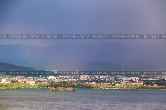 Town on the lake behind the foothills. Spring rain and storm in mountains. Green spring hills of Slovakia. Spring stormy scene. Стоковое фото, агентство Ingram Publishing / Фотобанк Лори