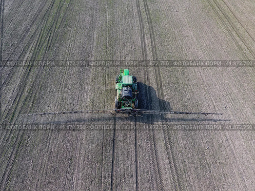 Tractor with hinged system of spraying pesticides. Fertilizing with a tractor, in the form of an aerosol, on the field of winter wheat. Стоковое фото, фотограф Леонид Еремейчук / Фотобанк Лори