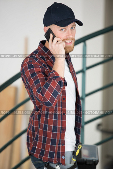 tradesman entering premises talking on his smartphone. Стоковое фото, агентство Ingram Publishing / Фотобанк Лори