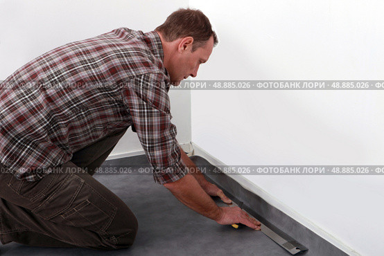 Tradesman laying down linoleum flooring. Стоковое фото, агентство Ingram Publishing / Фотобанк Лори