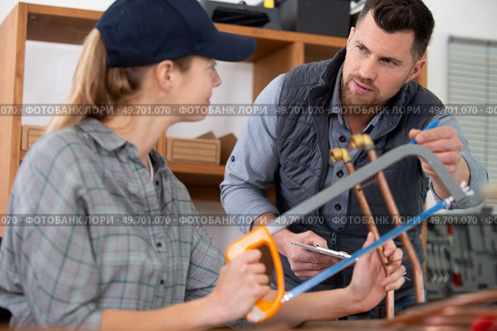 tradeswoman cutting copper pipe with hacksaw. Стоковое фото, агентство Ingram Publishing / Фотобанк Лори