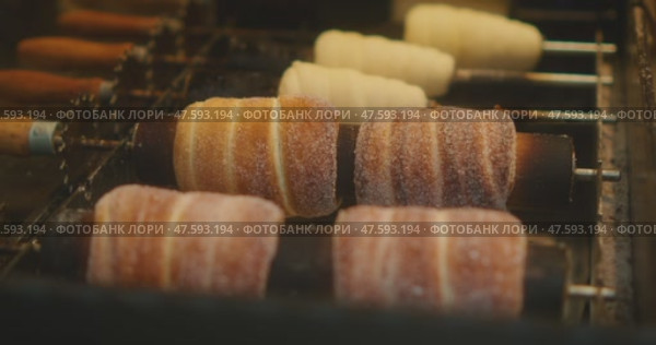 Traditional chimney cakes are being grilled over open flames at a street market in Prague, covered in sugar and cinnamon. Стоковое видео, видеограф Igor Tichonow / Фотобанк Лори