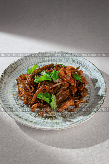 Traditional Korean dish made of stir-fried seaweed and pork with onions, red chili sauce and fresh herbs served on a rustic ceramic plate. Стоковое фото, фотограф Aleksandr Gavrilychev / Фотобанк Лори
