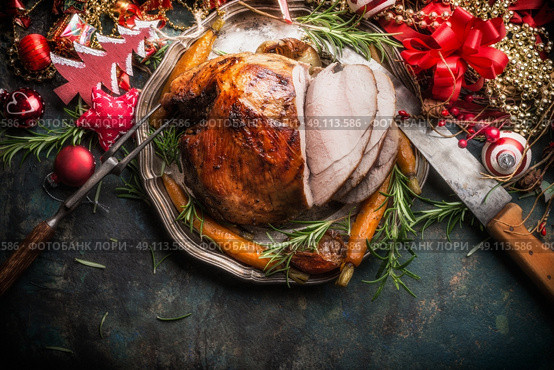 Traditional sliced roasted glazed Christmas ham with holiday festive decoration on dark rustic background, top view, border . Стоковое фото, агентство Ingram Publishing / Фотобанк Лори