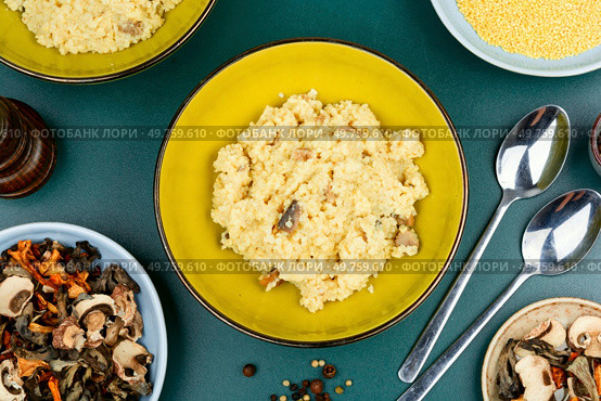 Traditional Ukrainian millet porridge with mushrooms in a ceramic dish. Top view.. Pearl millet with fried mushrooms. Стоковое фото, агентство Ingram Publishing / Фотобанк Лори