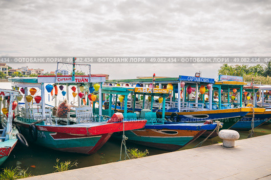 Traditional wooden Vietnamese boats on the Thu Bon River in the old town in Hoi An in Vietnam. Vietnam, Hoi An - December 1, 2024. Редакционное фото, фотограф Корчагина Анастасия / Фотобанк Лори