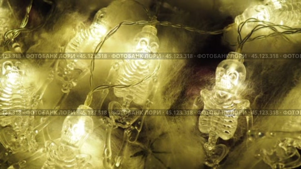 Transparent skeletons glowing yellow, close-up. Transform your space with a whimsical garland featuring glowing skeleton skulls and bones, perfect for Halloween festivities and ambiance. Horror theme. Стоковое видео, видеограф Юлия Петровская / Фотобанк Лори