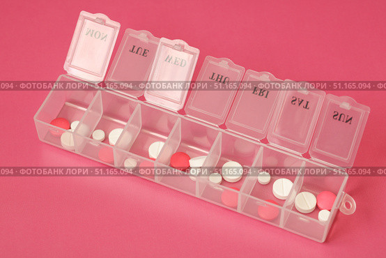 Transparent weekly pill organizer containing various pills on pink background. Стоковое фото, фотограф Дмитрий Цветков / Фотобанк Лори