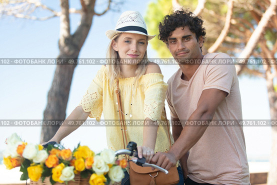 trendy couple posing on their bike with basket of flowers. Стоковое фото, агентство Ingram Publishing / Фотобанк Лори