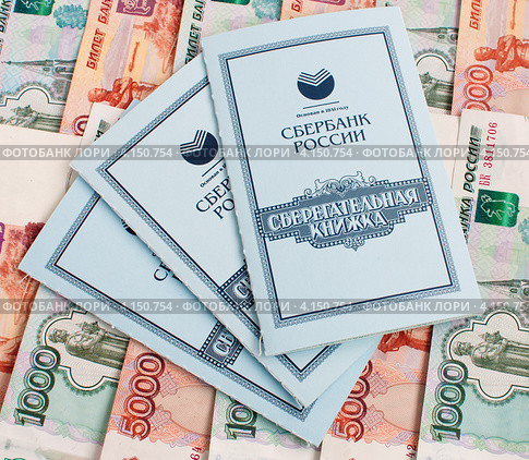 Три сберегательные книжки лежат на российских деньгах (2012 год). Редакционное фото, фотограф Игорь Низов / Фотобанк Лори