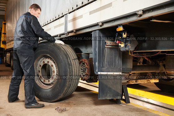Truck repair service. Mechanic works with tire in truck workshop. Стоковое фото, фотограф Дмитрий Калиновский / Фотобанк Лори