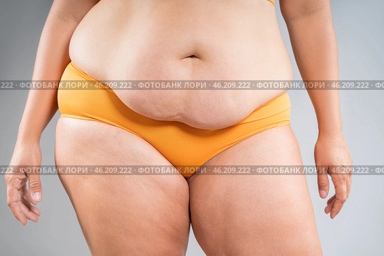 Tummy tuck, flabby skin on a fat belly, abdomen with obesity and cellulite, saggy stomach, plastic surgery concept on gray background. Стоковое фото, фотограф Станислав Тарко / Фотобанк Лори