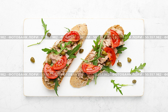 Tuna caper toasts with arugula, tomatoes and whole rye bread, top view. Стоковое фото, агентство Ingram Publishing / Фотобанк Лори