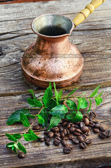 Turk and coffee beans. empty cezve on wooden background with scattered coffee beans and mint. Стоковое фото, агентство Ingram Publishing / Фотобанк Лори