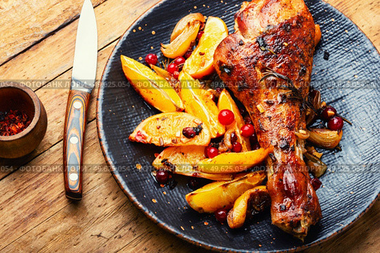 Turkey meat baked in oranges. Roasted turkey leg on rustic wooden table. Grilled turkey drumstick with citrus. Стоковое фото, агентство Ingram Publishing / Фотобанк Лори