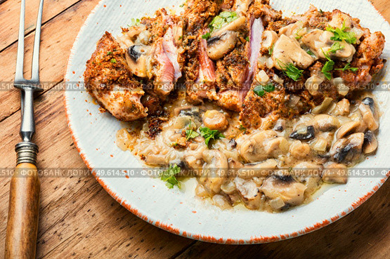Turkey meat in cheese breading with mushroom sauce on rustic wooden table. Turkey schnitzel with fried mushrooms. Стоковое фото, агентство Ingram Publishing / Фотобанк Лори