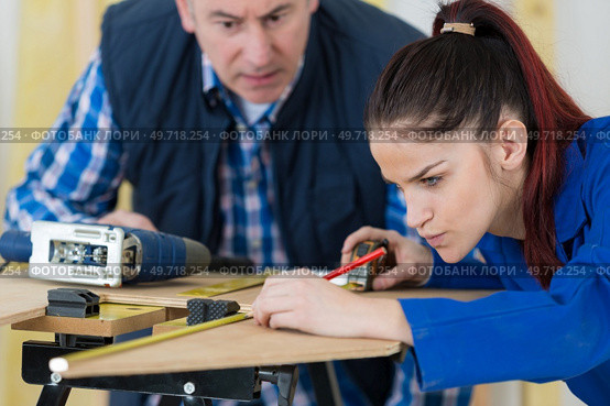 Tutor watching apprentice measuring wood. Стоковое фото, агентство Ingram Publishing / Фотобанк Лори