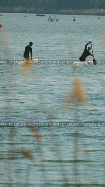 Two canoe athletes powerfully float on sparkling waters framed by tall grasses. Preparation for the competition athletes watermen. Стоковое видео, видеограф Воловодов Владимир / Фотобанк Лори