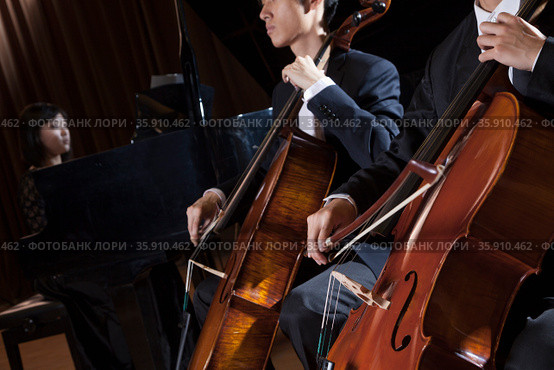 Two cellists playing the cello during a performance. Стоковое фото, агентство Ingram Publishing / Фотобанк Лори