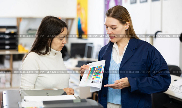 Two employees of printing house are discussing quality of plotter printing on color table. Стоковое фото, фотограф Яков Филимонов / Фотобанк Лори