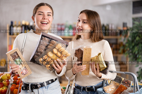 Two girls in store while shopping, choose sweets and chat sweetly. Стоковое фото, фотограф Яков Филимонов / Фотобанк Лори
