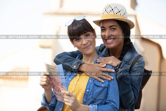 two happy women hugging and looking at the map. Стоковое фото, агентство Ingram Publishing / Фотобанк Лори