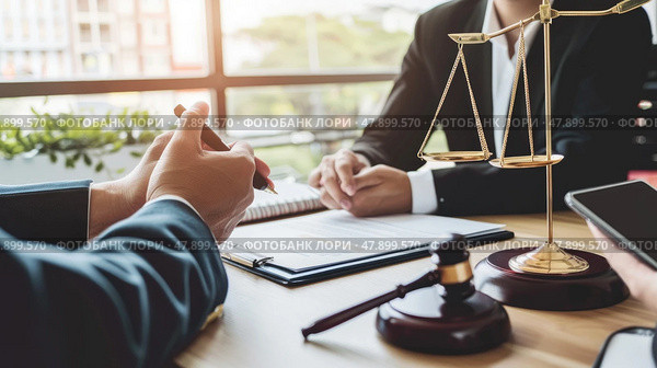 Two individuals are seated at a table located in front of a scale of justice, engaging in discussions or negotiations. The symbolic representation of justice is prominent in the background. Стоковое AI-изображение, AI-художник Данила Большаков / Фотобанк Лори