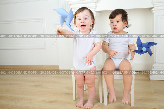 Two little kids sitting on white chairs with blue paper whirligigs. Стоковое фото, фотограф Losevsky Pavel / Фотобанк Лори