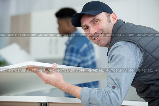 two men assembling a kitchen cupboard. Стоковое фото, агентство Ingram Publishing / Фотобанк Лори