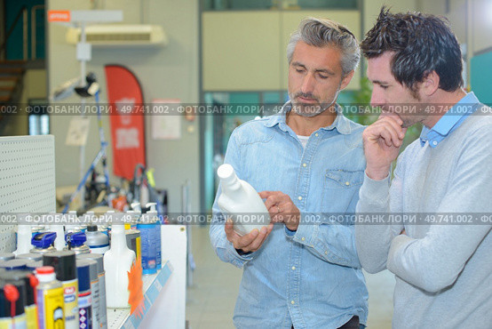 Two men looking at label of mechanical product. Стоковое фото, агентство Ingram Publishing / Фотобанк Лори