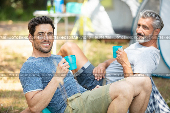 two men relaxing and having a drink by their tents. Стоковое фото, агентство Ingram Publishing / Фотобанк Лори