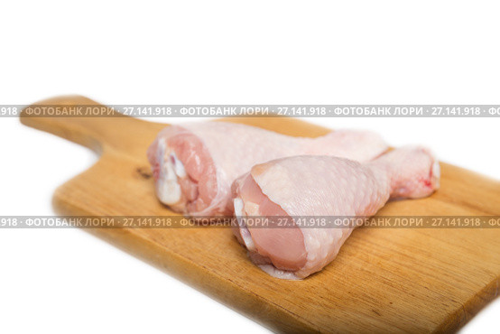 Two raw chicken drumsticks on a cutting board on a white background. Стоковое фото, фотограф Юлия Бабкина / Фотобанк Лори