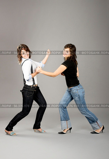 Two young beautiful sisters having fun simulating a fight  - This models are true twins. Стоковое фото, агентство Ingram Publishing / Фотобанк Лори