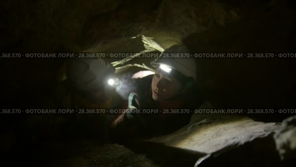 Two young hikers explorers stuck in the narrow hole in dark cave. Стоковое видео, видеограф Константин Шишкин / Фотобанк Лори