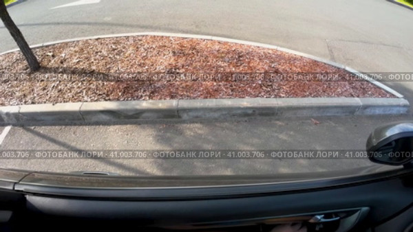 У машины на парковке в городе опускается стекло двери и открывается боковое зеркало. Вид с крыши машины в солнечный день лета (2023 год). Редакционное видео, видеограф Sergei Gorin / Фотобанк Лори