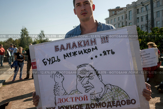 Участник Всероссийского митинга обманутых дольщиков строительной компании СУ-155 стоит с плакатом на Суворовской площади города Москвы, Россия (2015 год). Редакционное фото, фотограф Николай Винокуров / Фотобанк Лори