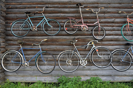 Uchma village, 54, Myshkin district, Yaroslavl region, Russia, July 25, 2024: Collection of old bicycles on wall of wooden log old barn of Private Museum of fate of Russian village of married couple Vasily Smirnov and Elena Naumova. Редакционное фото, фотограф Алексей Антипов / Фотобанк Лори