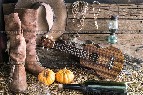 ukulele with american west rodeo brown cowboy hat and leather boots in vintage ranch barn studio background, Still life style. Стоковое фото, агентство Ingram Publishing / Фотобанк Лори