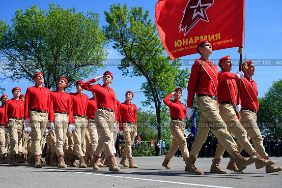 Юнармейцы строем маршируют по плацу. Молодые ребята и девчата в красных беретах несут знамя юнармии. Патриотическое воспитание. (2019 год). Редакционное фото, фотограф Евгений Зимин / Фотобанк Лори
