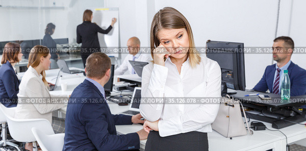 Unhappy young woman foreground in busy open plan office. Стоковое фото, фотограф Яков Филимонов / Фотобанк Лори