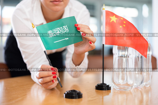 Unrecognizable girl sets midget flags of Chinа and Saudi Arabia before international negotiations. Стоковое фото, фотограф Яков Филимонов / Фотобанк Лори