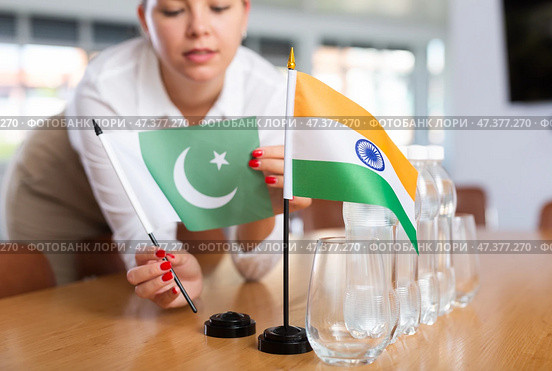 Unrecognizable girl sets midget flags of India and Pakistan before international negotiations. Стоковое фото, фотограф Яков Филимонов / Фотобанк Лори