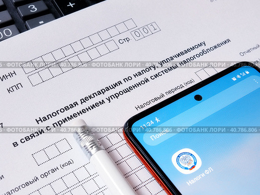 Упрощенная система налогообложения. Налоговая декларация, электронное приложение "Налоги" и карандаш. Редакционное фото, фотограф Татьяна Т / Фотобанк Лори